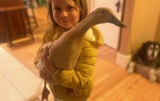 A young girl and a duck inside her house